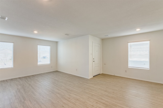 spare room with light hardwood / wood-style floors and a textured ceiling