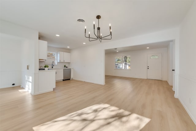 unfurnished living room featuring sink, an inviting chandelier, and light wood-type flooring