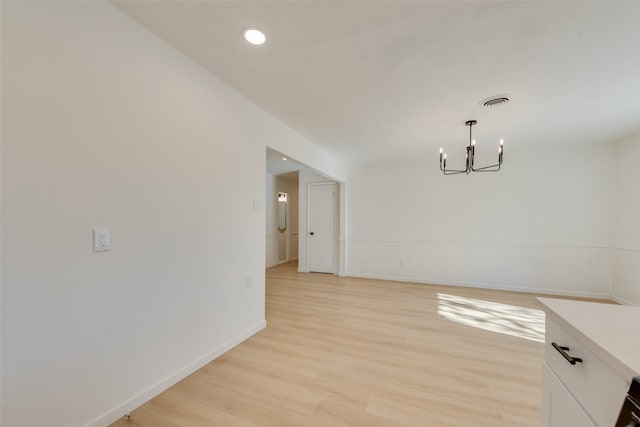 unfurnished dining area featuring a notable chandelier and light wood-type flooring