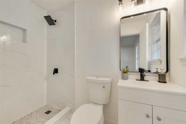 bathroom with vanity, toilet, and a tile shower