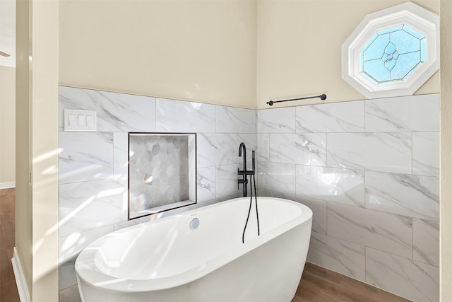 bathroom with hardwood / wood-style floors, a tub to relax in, and tile walls