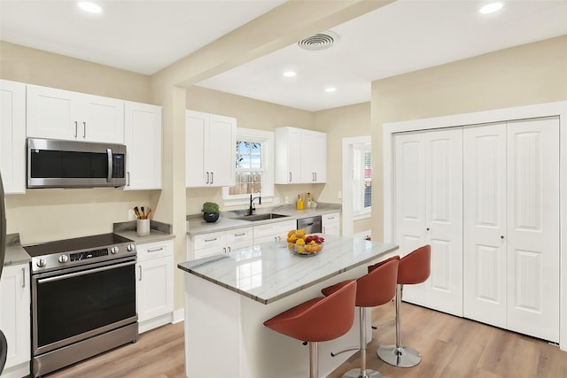 kitchen featuring stainless steel appliances, white cabinetry, a center island, and sink