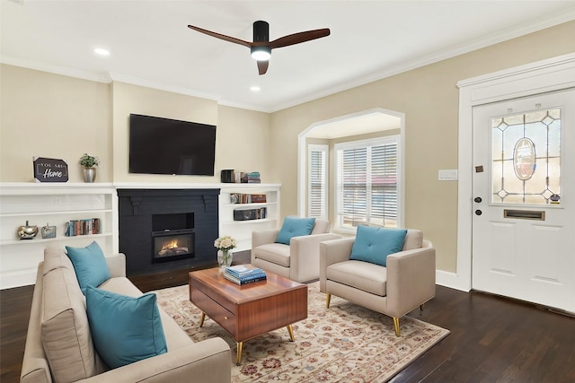 living room with crown molding, dark hardwood / wood-style flooring, ceiling fan, and a fireplace