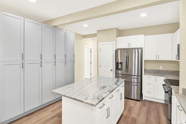 kitchen with light hardwood / wood-style flooring, appliances with stainless steel finishes, light stone countertops, white cabinets, and a kitchen island