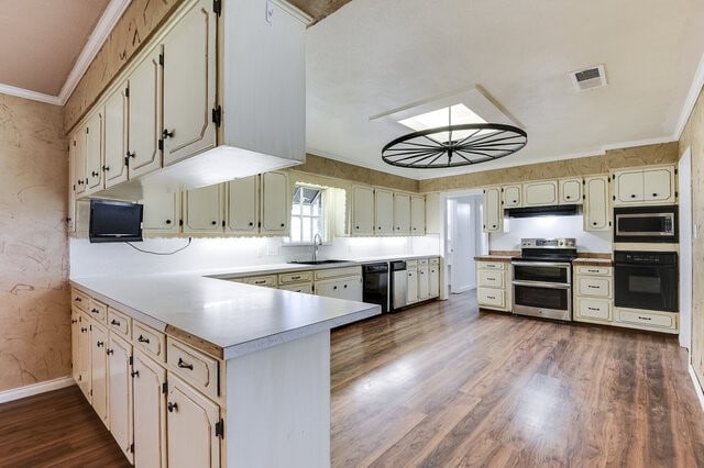 kitchen with crown molding, sink, black appliances, and dark hardwood / wood-style floors