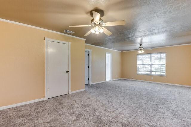 carpeted spare room featuring a textured ceiling, ceiling fan, and crown molding