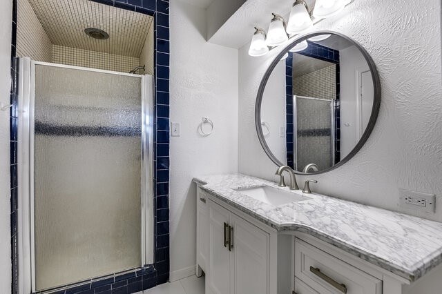 bathroom with tile patterned floors, vanity, and an enclosed shower