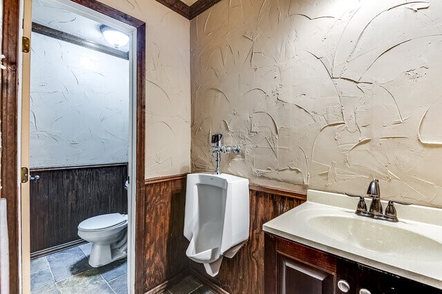 bathroom featuring wood walls, vanity, and toilet