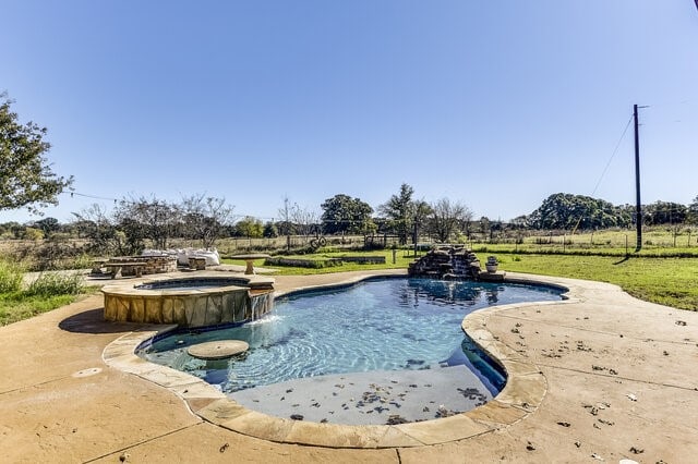 view of swimming pool with pool water feature, a patio area, and an in ground hot tub