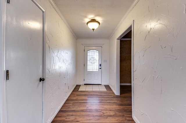 entryway with wood-type flooring and crown molding