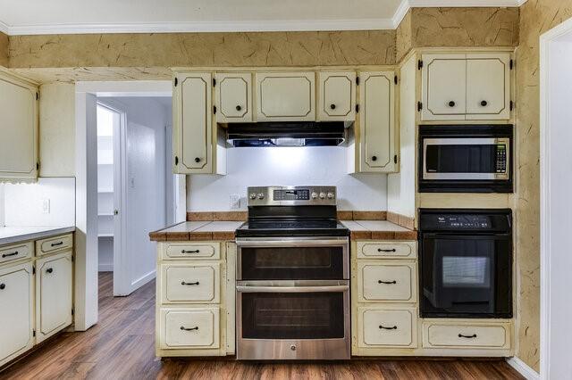 kitchen with cream cabinetry, dark hardwood / wood-style floors, and stainless steel appliances