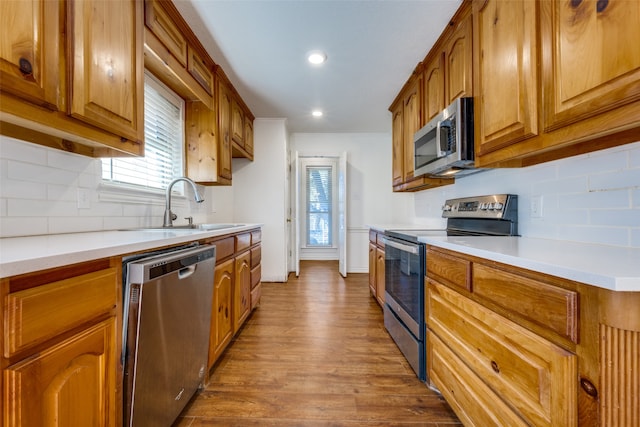 kitchen with decorative backsplash, hardwood / wood-style floors, stainless steel appliances, and sink