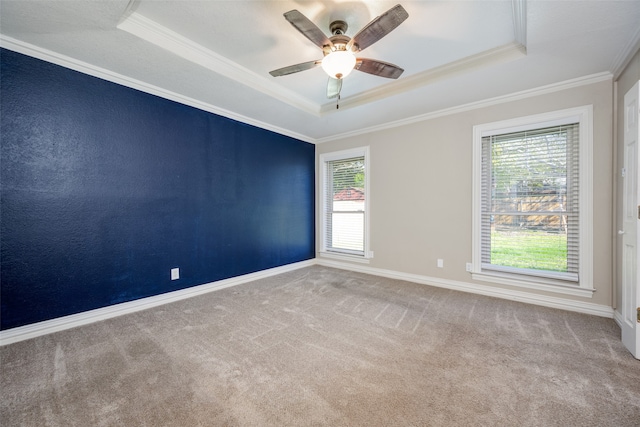 carpeted spare room with a tray ceiling, crown molding, and ceiling fan