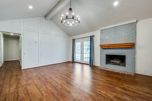 unfurnished living room with french doors, lofted ceiling with beams, a brick fireplace, dark hardwood / wood-style floors, and a notable chandelier