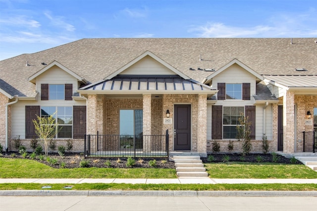 view of front of home featuring brick siding and a shingled roof