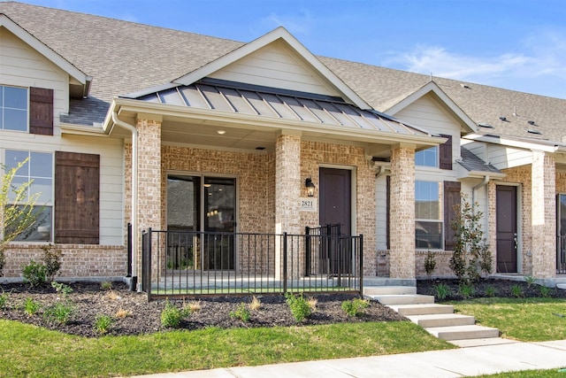 view of front of property with a standing seam roof, a porch, metal roof, brick siding, and a shingled roof