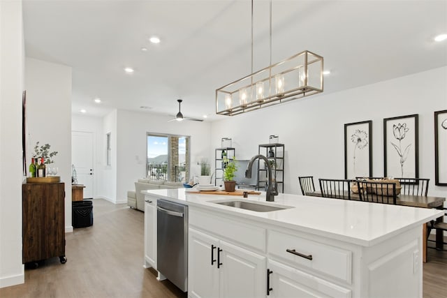 kitchen featuring white cabinetry, sink, hanging light fixtures, light hardwood / wood-style flooring, and an island with sink