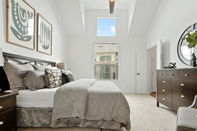 bedroom with a high ceiling, light colored carpet, and ceiling fan