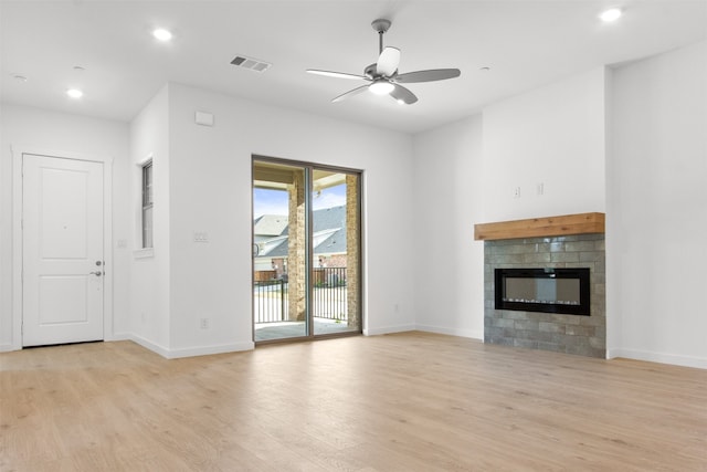 unfurnished living room with baseboards, a glass covered fireplace, visible vents, and light wood-type flooring