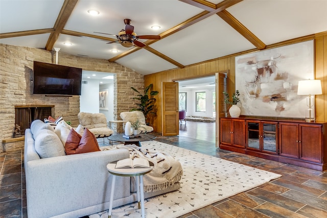 living room with lofted ceiling with beams, wood walls, a fireplace, and ceiling fan