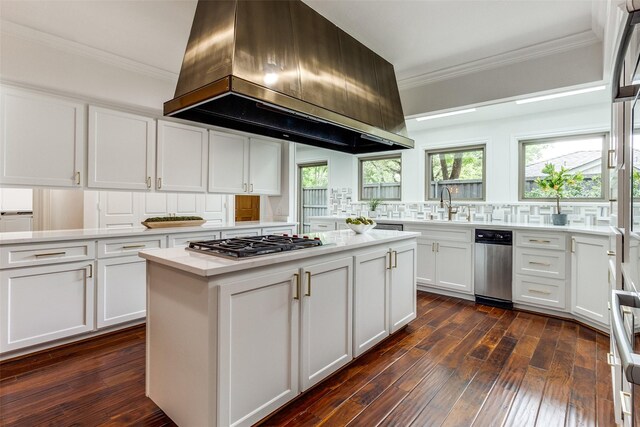 kitchen featuring a center island, island range hood, white cabinets, stainless steel gas cooktop, and ornamental molding