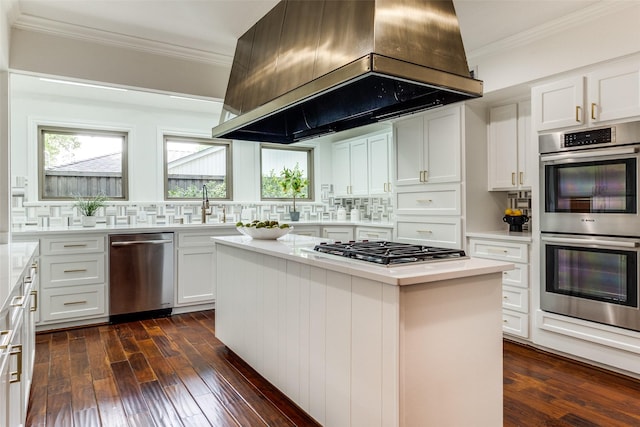 kitchen featuring appliances with stainless steel finishes, island range hood, white cabinetry, and a kitchen island