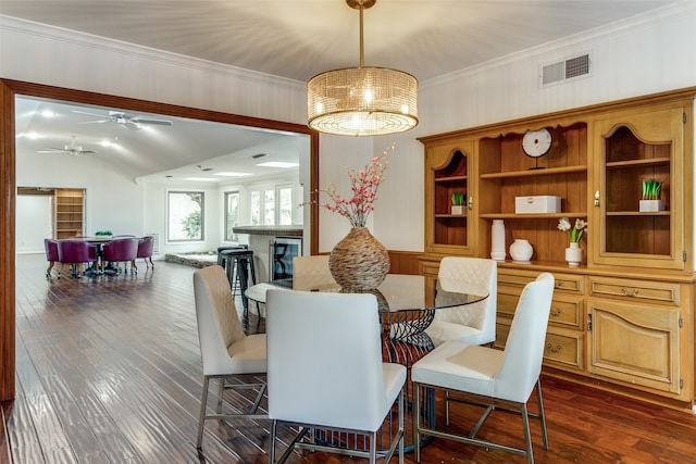 dining room with vaulted ceiling, crown molding, ceiling fan, and dark wood-type flooring