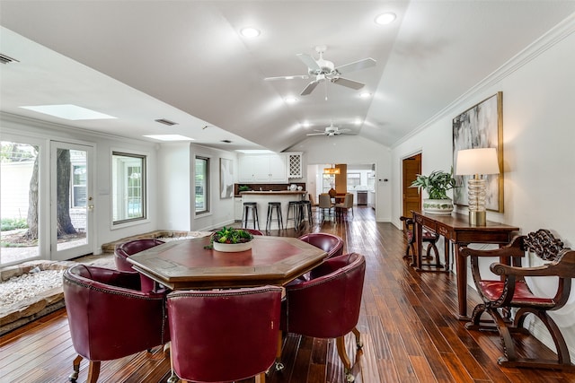 dining area featuring ceiling fan, vaulted ceiling with skylight, dark hardwood / wood-style floors, and ornamental molding