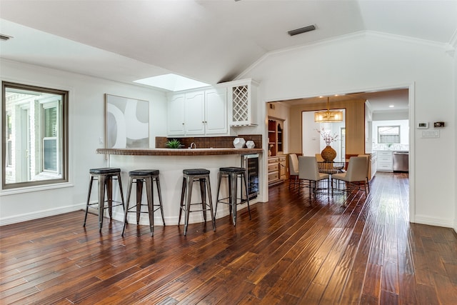 kitchen featuring kitchen peninsula, a kitchen breakfast bar, white cabinetry, and a wealth of natural light