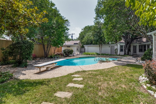 view of swimming pool with a diving board and a lawn