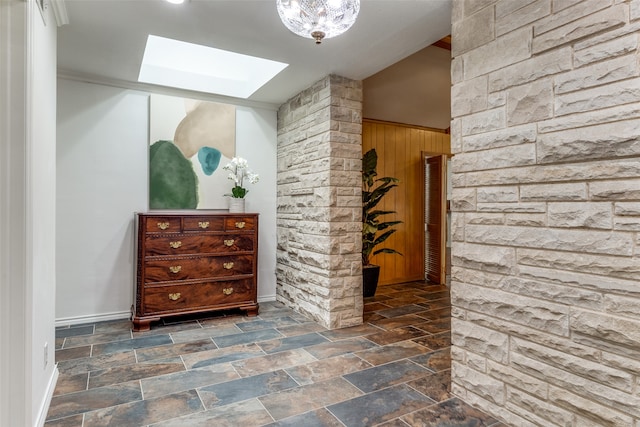 hallway featuring lofted ceiling with skylight and wooden walls