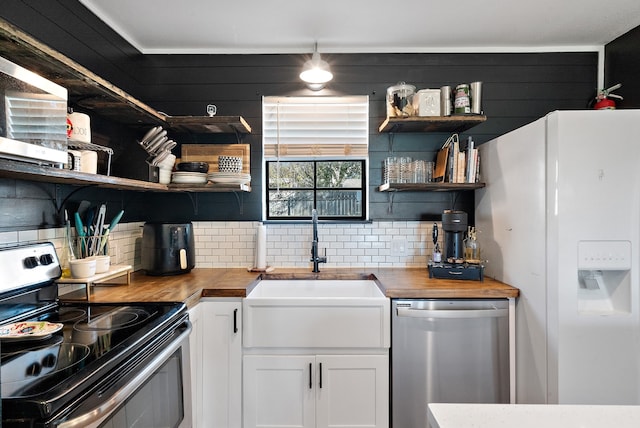 kitchen featuring stainless steel appliances, white cabinetry, butcher block counters, and sink