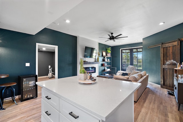 kitchen featuring ceiling fan, a center island, a barn door, light hardwood / wood-style flooring, and white cabinets