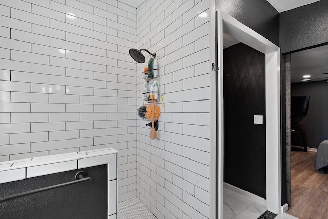 bathroom with a tile shower and hardwood / wood-style flooring