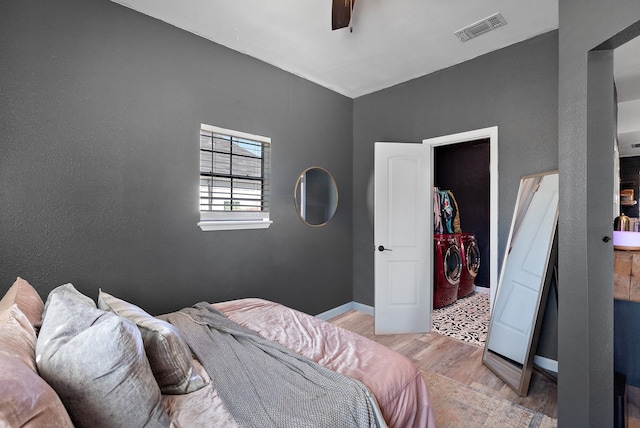 bedroom featuring washing machine and clothes dryer, a walk in closet, ceiling fan, light wood-type flooring, and a closet