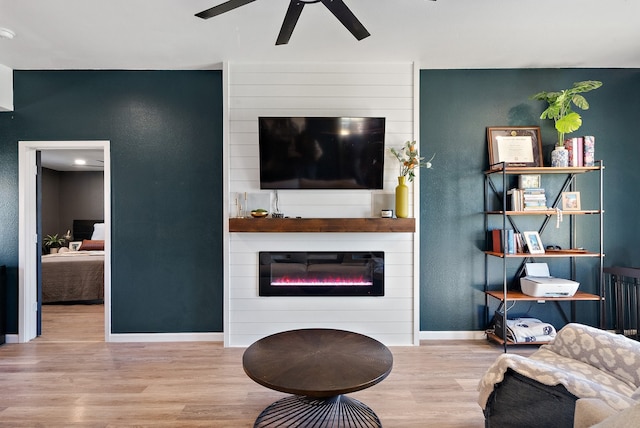 living room with a fireplace, wood-type flooring, and ceiling fan