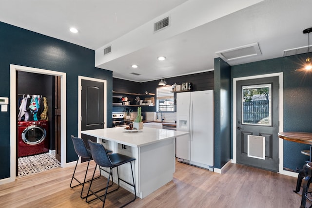 kitchen featuring a center island, stainless steel range with electric cooktop, light hardwood / wood-style floors, and white refrigerator with ice dispenser