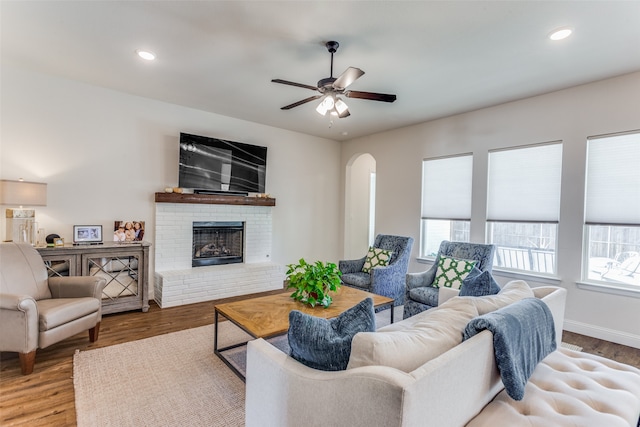 living room with ceiling fan, light hardwood / wood-style floors, and a brick fireplace