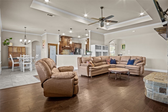 living room with a raised ceiling, crown molding, wood-type flooring, and ceiling fan with notable chandelier