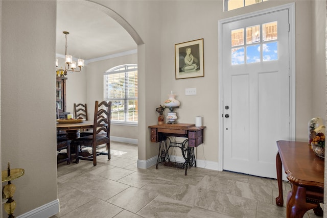 entrance foyer with ornamental molding and a chandelier