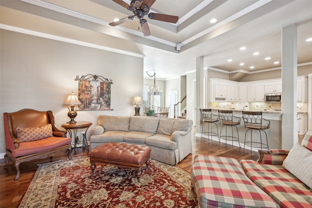 living room with ceiling fan with notable chandelier, crown molding, and light hardwood / wood-style flooring