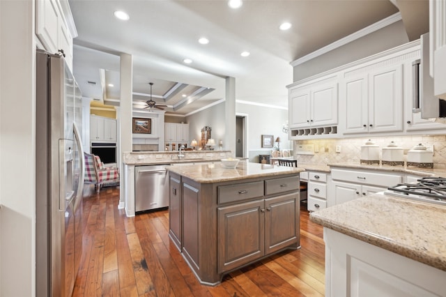 kitchen featuring appliances with stainless steel finishes, ceiling fan, dark wood-type flooring, a center island, and white cabinetry