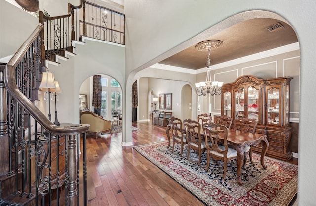 dining area featuring a textured ceiling, crown molding, dark wood-type flooring, and a chandelier