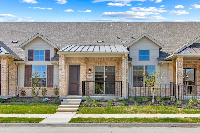 multi unit property with brick siding, a standing seam roof, and fence