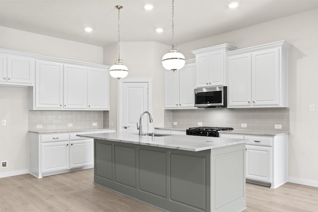 kitchen with stove, a sink, stainless steel microwave, baseboards, and light wood-style flooring