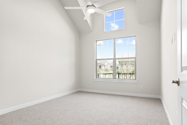 carpeted empty room with a high ceiling, a ceiling fan, and baseboards