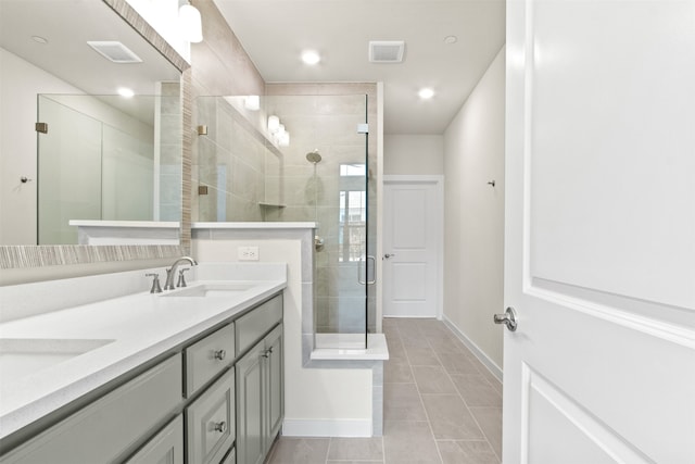 bathroom with a sink, double vanity, baseboards, visible vents, and a shower stall