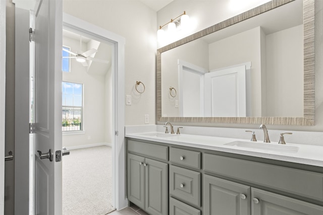 full bath featuring double vanity, a ceiling fan, baseboards, and a sink
