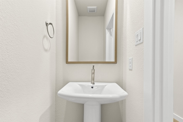 bathroom featuring a textured wall and a sink