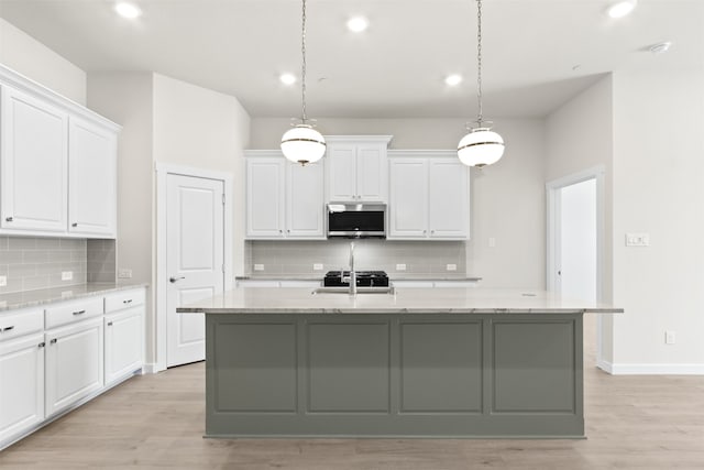 kitchen with stainless steel microwave, light wood finished floors, decorative backsplash, and recessed lighting